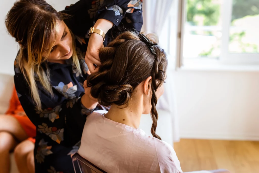 Coiffeuse réalisant un chignon tressé pour une mariée, préparation beauté avec Le Fauteuil de Norma