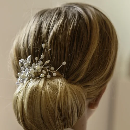 Chignon bas élégant pour coiffure de mariée, orné de perles, réalisé par Norma